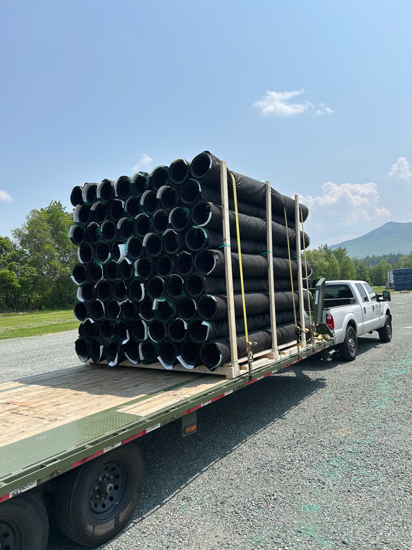 Rolls of black corrugated drainage pipe on a flatbed