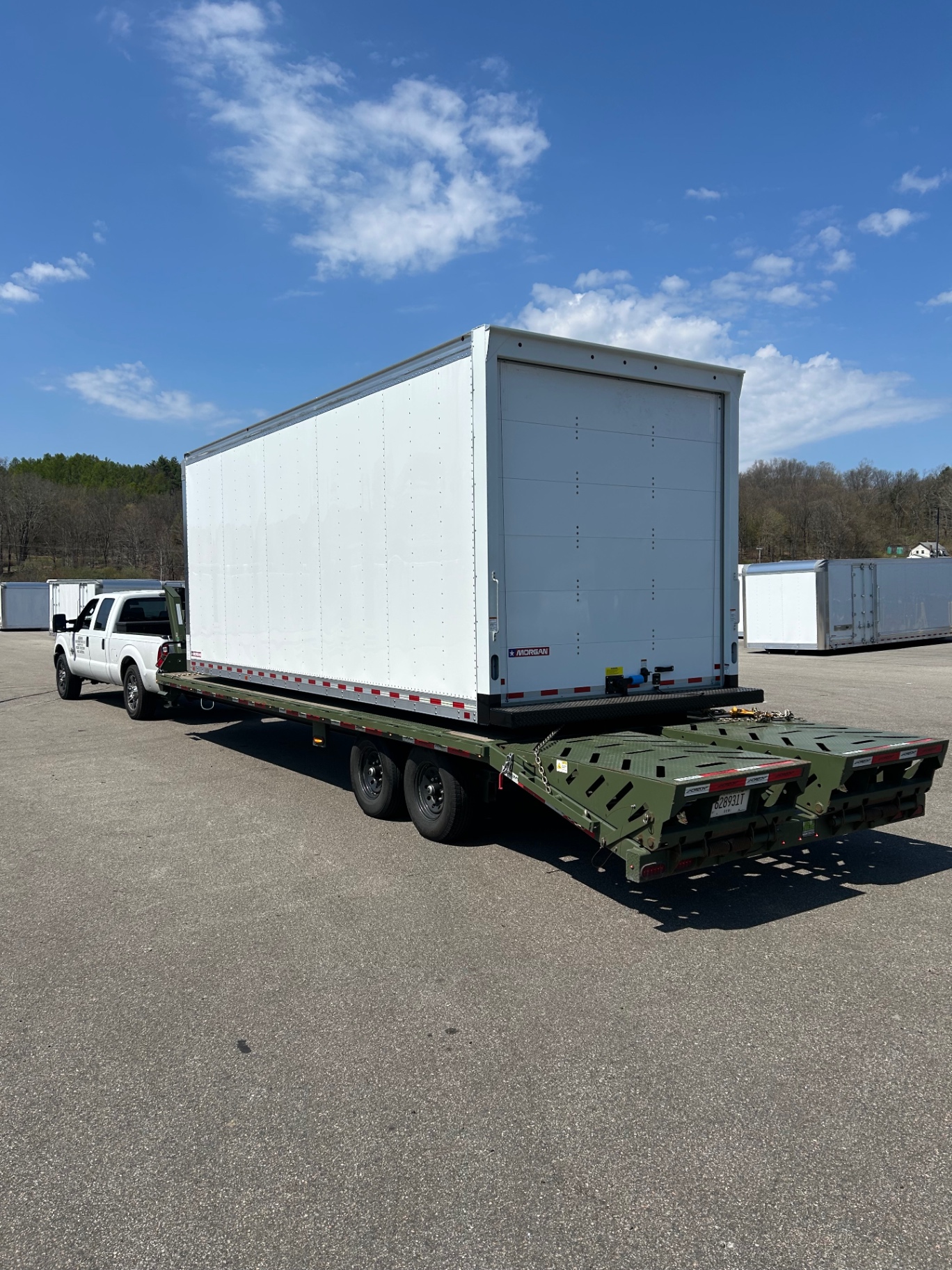 White Morgan box truck body hauled on a gooseneck trailer